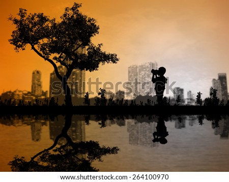 Silhouettes baby boy with camera shooting tree over blurred City Scape. Likened to a single tree in a big city kid I kept looking. Environmental concept