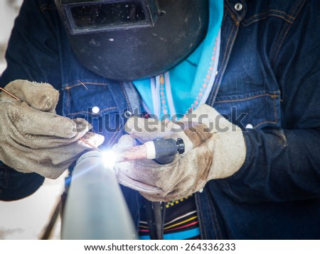 Welder on galvanized pipe in shop at substation