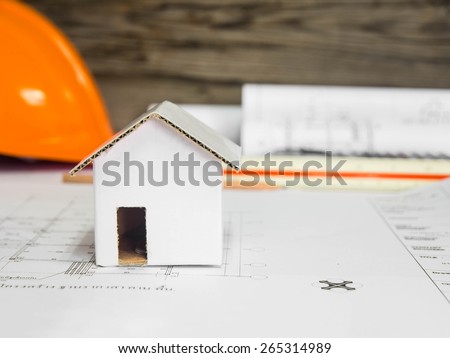 A house model over blurred architectural blueprint of office building