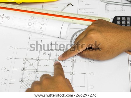hand pointing architectural blueprint. over blurred architectural blueprint of office building
