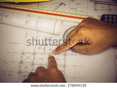 hand pointing architectural blueprint. over blurred architectural blueprint of office building
