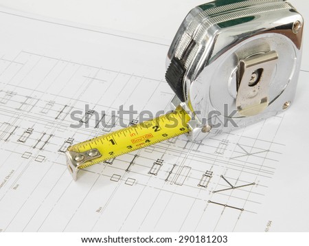 A tape measure over blurred architectural blueprint of office building