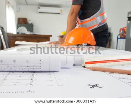 Blueprint of office building over blurred adult male engineer examining documents