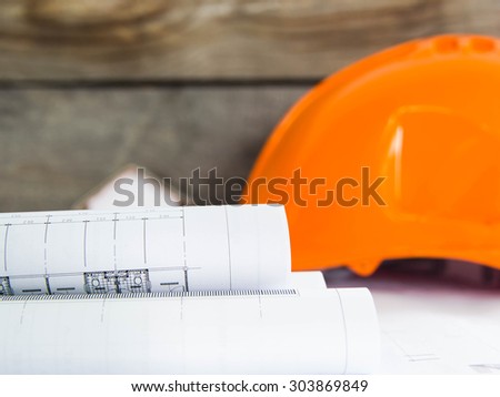 Blueprint of office building over blurred Safety orange hat and blueprint