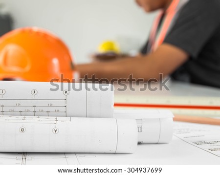 Blueprint of office building over blurred adult male engineer examining documents