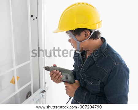 Construction worker drilling hole door Repair in house. interior design and home renovation concept
