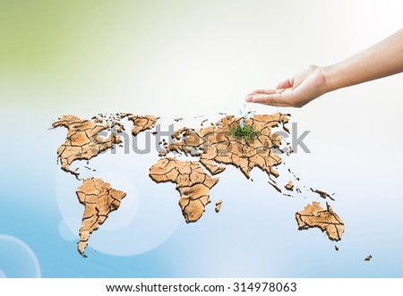 Human hands drop water on dry world map engender Moisturizing makes the green grass grow over Blurred nature background. Ecology concept. Save the planet and healthy environment concept.
