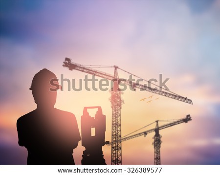 silhouette black man survey and civil engineer stand on ground working in a land building site over Blurred construction worker on construction site. examination, inspection, survey