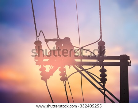 Silhouette electrical workers are installing high voltage systems over blur night city