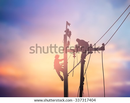 Silhouette electrical workers are installing high voltage systems over blur night city