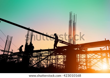 Silhouette of construction workers working on scaffolding at a high level by the standards set must include a safety belt for safety. Heavy industry And Safety at Work concept.