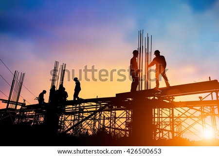 Silhouette engineer standing orders for construction crews to work on high ground  heavy industry and safety at work concept over blurred natural background sunset pastel