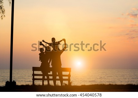 Silhouette Asian family standing selfie camera family consists of parents and children happy. The family enjoyed a holiday Holiday over blurred beautiful nature sea.Concept of friendly family.