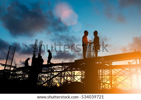 Success joint venture business growth, progress and potential concepts.Silhouette businessmen shake hands finishing a deal between businesses over blurred employees at Construction Site.flare light