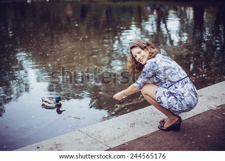 Girl feeding a duck in the Park by the pond