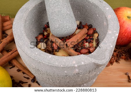 stone pestle grinding anise, nuts, pepper and cloves on wood