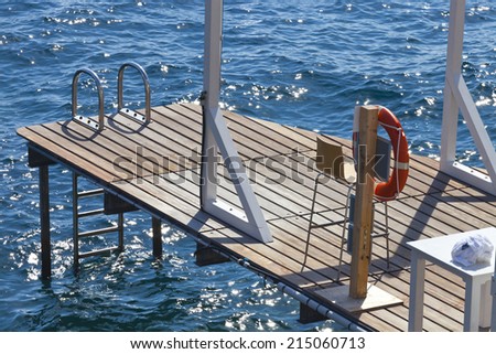 Wooden  sea jetty with rescue wheel and metal ladder
