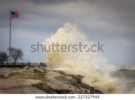 Crashing waves against shoreline with view of American Flag
