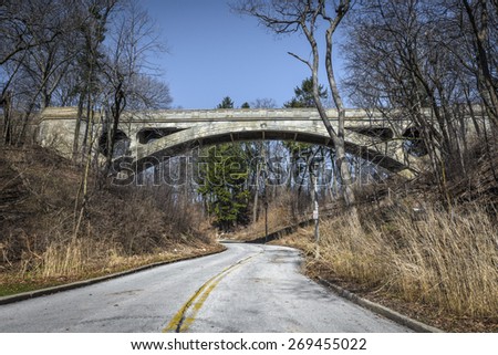 Street view of walking bridge with street leading line to arch of bridge in Milwaukee, WI with bright blue sky