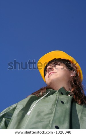 Woman with yellow safety helmet and green plastic raincoat