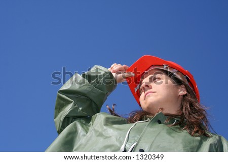 Woman holding red safety helmet and with green plastic raincoat