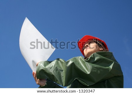 Woman holding plans with red safety helmet and green plastic raincoat