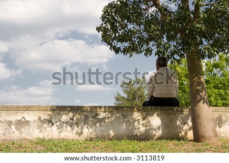 Man seated under a tree catching some shade on a hot day