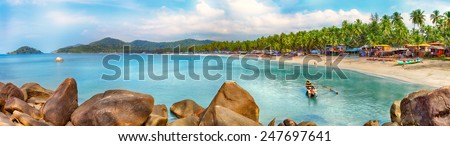 Beautiful Goa province beach in India with fishing boats and stones in the sea