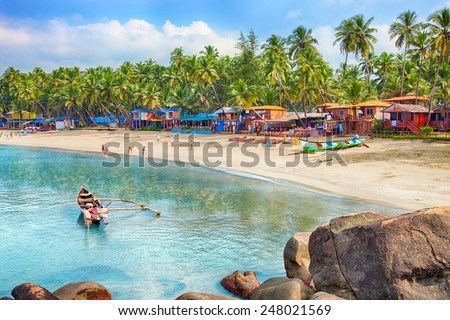 Beautiful Goa province beach in India with fishing boats and stones in the sea