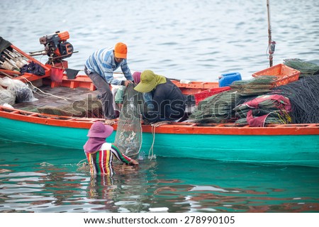 KEP PROVINCE, CAMBODIA- DECEMBER 2014: Traditional asian fishing. Cambodian men on the fishing boat pass the catch of  blue crabs to woman for sale