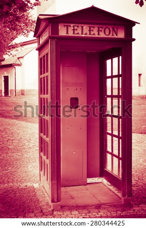 Change for mobile call centers - old telephone booth without telephone machine with Telefon sign - dark marsala red tinted grunge vintage effect photo