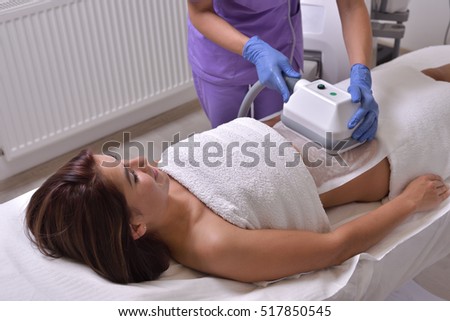 Pretty young woman getting cryolipolyse treatment in cosmetic cabinet