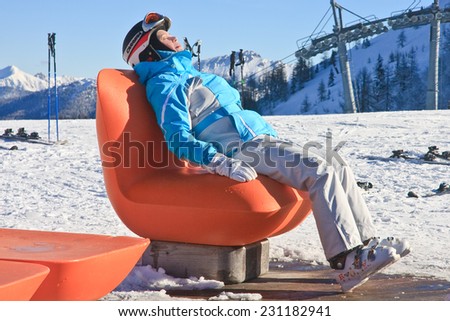 SCHLADMING, AUSTRIA - JANUARY 23, 2014: View of woman resting on chair in mountains of Schladming winter resort, Austrian Alps on January 23, 2014
