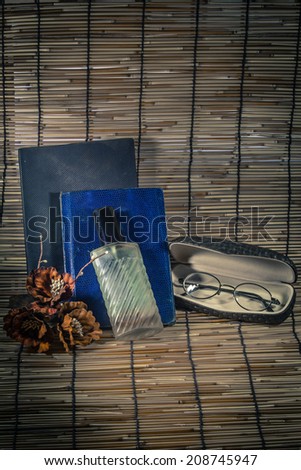 Vintage still life with old spectacles and perfume on book.