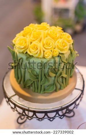 Yellow butter cream frosting handmade roses on a round cake.