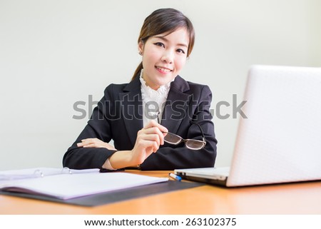 Smiling confident businesswoman sitting at her desk in the office in front of a laptop computer.