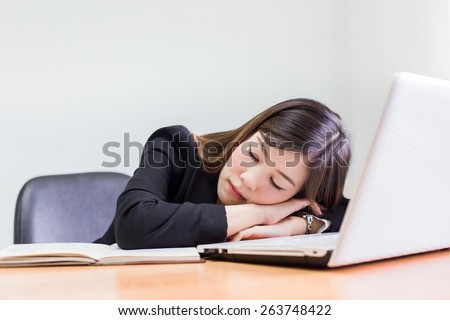 business asian woman taking a nap, tired from work, sleeping in front of laptop, lying on her hands.