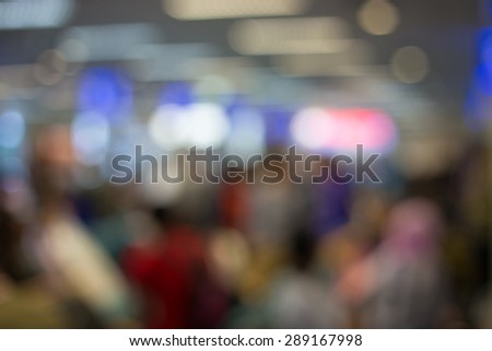 Blurred photo of an airport terminal with unrecognizible passengers passing by with luggage. Blurred background for topics of travel and transportation