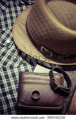 still life photography : Brown leather wallet, Leather wristbands, silver ring and adventure hat on jeans background, men casual concept, vintage and retro style