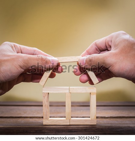 Businessman and hand build house blocks.