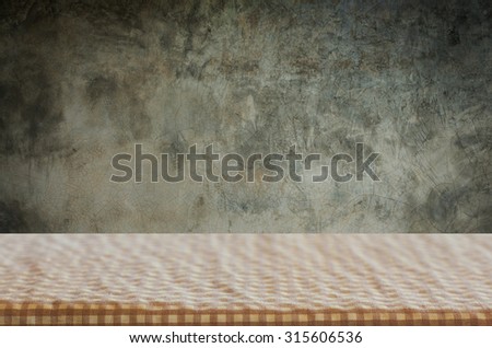 Empty table covered with red checked tablecloth over white cement wall background, for product display montage