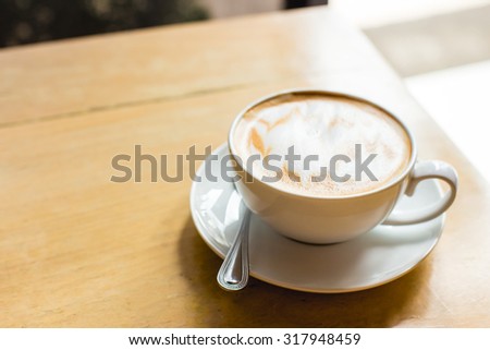 Hot latte art coffee cup on wooden table, vintage and retro style