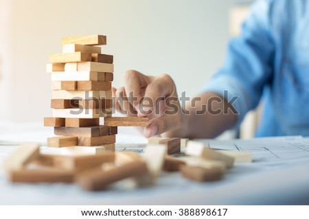 Planning, risk and strategy in business, businessman and engineer gambling placing wooden block on a tower