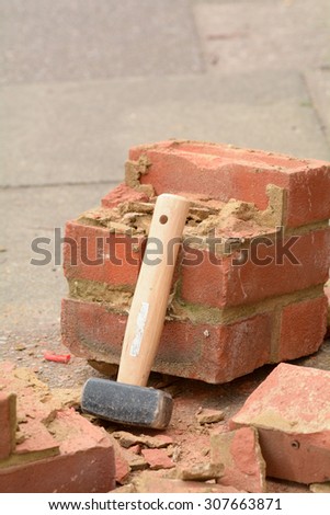Lump hammer leaning against broken brick wall