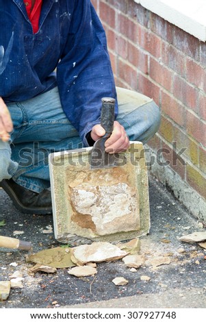 Bricklayer using lump hammer and bolster to clear old render off gate post topper