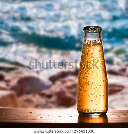 Cold bottled drink in focus with gas and amazing blurred view of sea