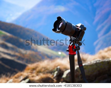 Modern professional camera on a tripod, outdoor photography in wildlife. Mountains background.