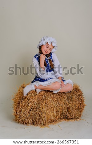 Girl in dress sitting on a rustic vintage straw bale