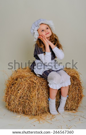 Girl in dress sitting on a rustic vintage straw bale