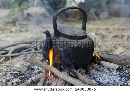 Boiling hot water with kettle on bonfire